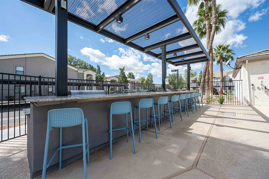 IMT Chandler - Bar style seating under a large shade and barbecues on the opposite side of seating