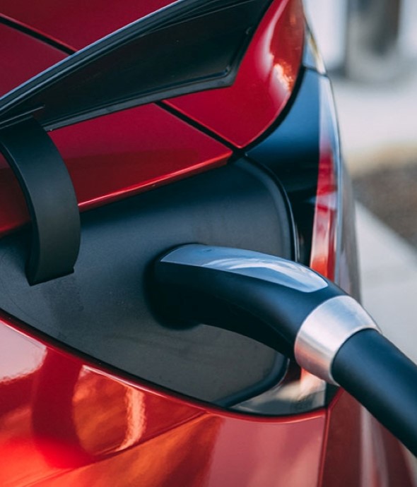 Electric vehicle charging with charger plugged in.